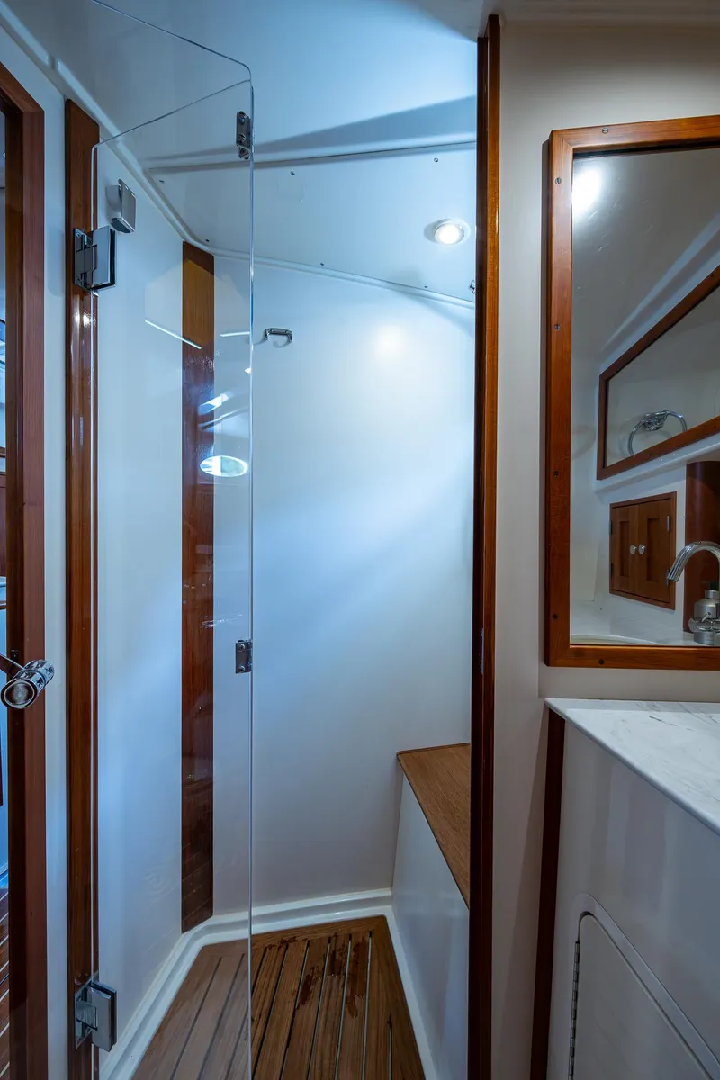 Slide: The Image of 2021 Hinckley Sport Boat 40 X interior bathroom with glass shower door and wooden accents. - 26