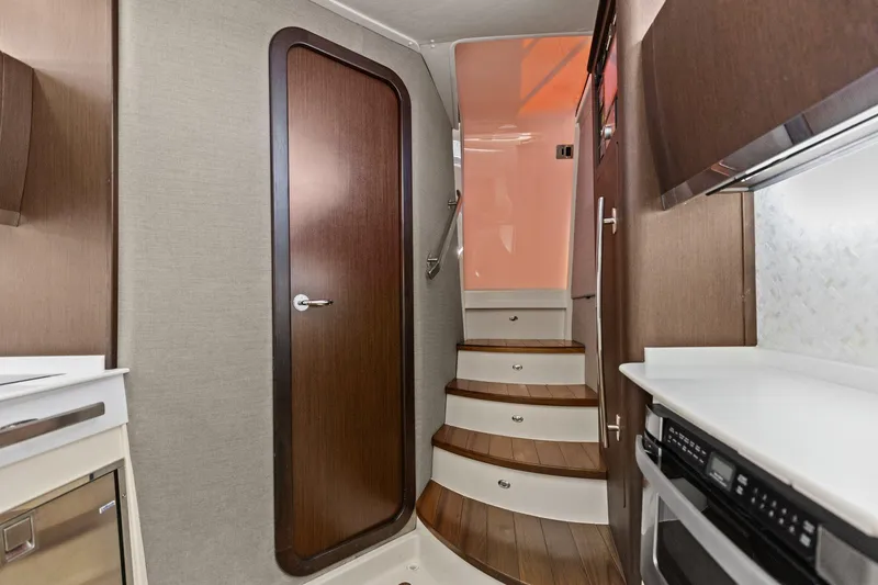 Slide: The Image of Interior of 2023 Grady-White Canyon 456 boat, featuring wooden stairs and modern cabinetry. - 19