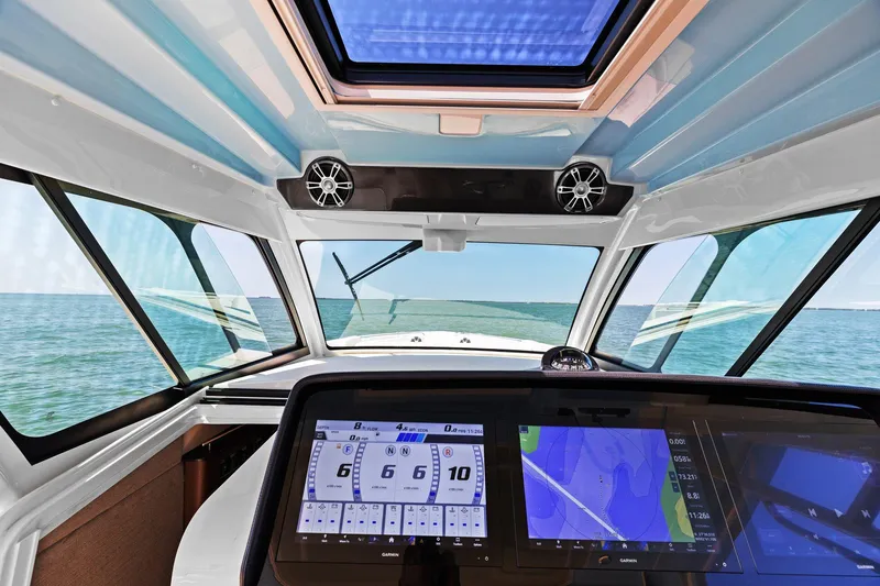 Slide: The Image of 2023 Grady-White Canyon 456 boat cockpit with navigation screens and ocean view. - 39