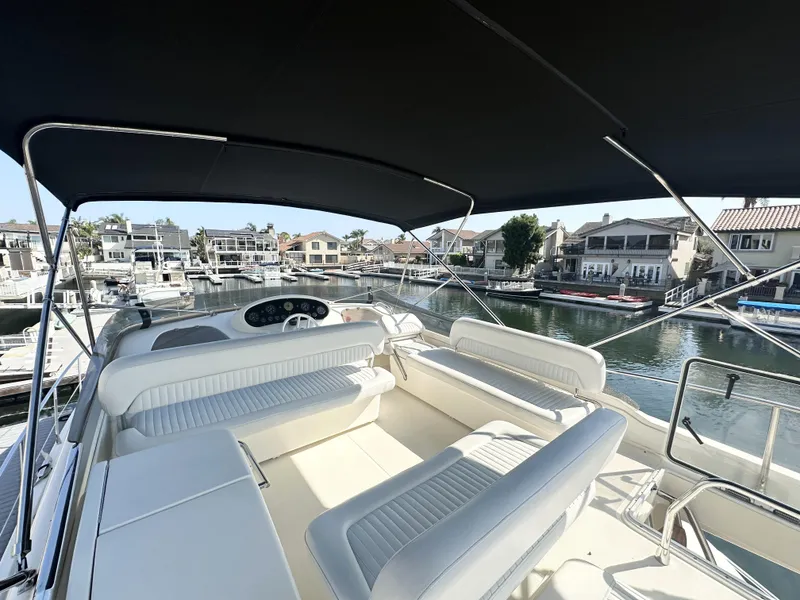 Slide: The Image of 1996 Azimut 54 yacht with spacious seating, docked in a marina under a black canopy. - 34