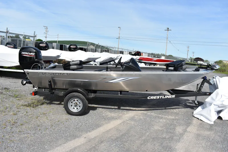 Slide: The Image of 2025 Crestliner 1700 Storm boat on trailer, parked outdoors, side view. - 1
