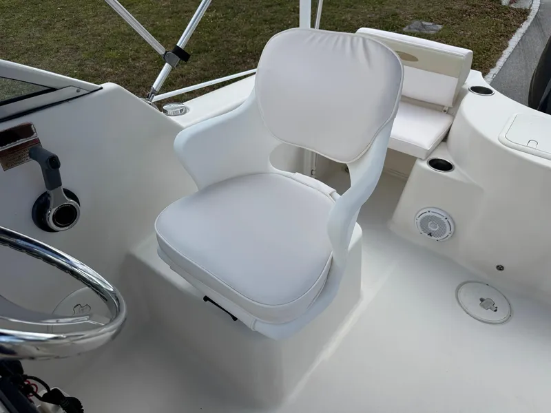 Slide: The Image of 2011 Cobia 215 Dual Console boat interior with white captain's chair and steering wheel. - 12