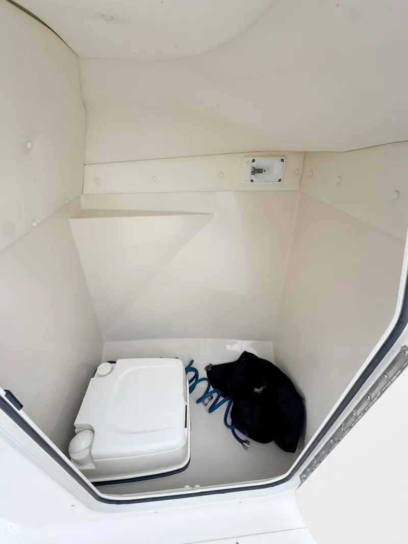 Slide: The Image of 2011 Cobia 215 Dual Console interior storage with portable toilet and gear. - 19