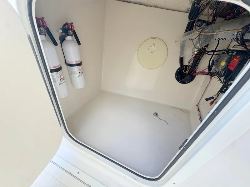 Slide: The Image of 2011 Cobia 215 Dual Console storage compartment with fire extinguishers and wiring. - 21