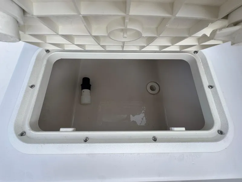 Slide: The Image of 2011 Cobia 215 Dual Console storage compartment with open lid and drainage feature. - 27