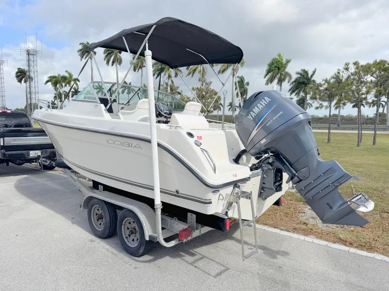 Slide: The Image of 2011 Cobia 215 Dual Console boat on trailer with Yamaha outboard motor, parked outdoors. - 3