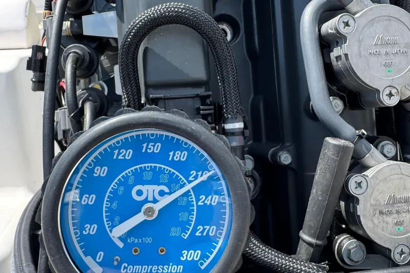 Slide: The Image of Close-up of a compression gauge on a 2011 Cobia 215 Dual Console boat engine. - 33