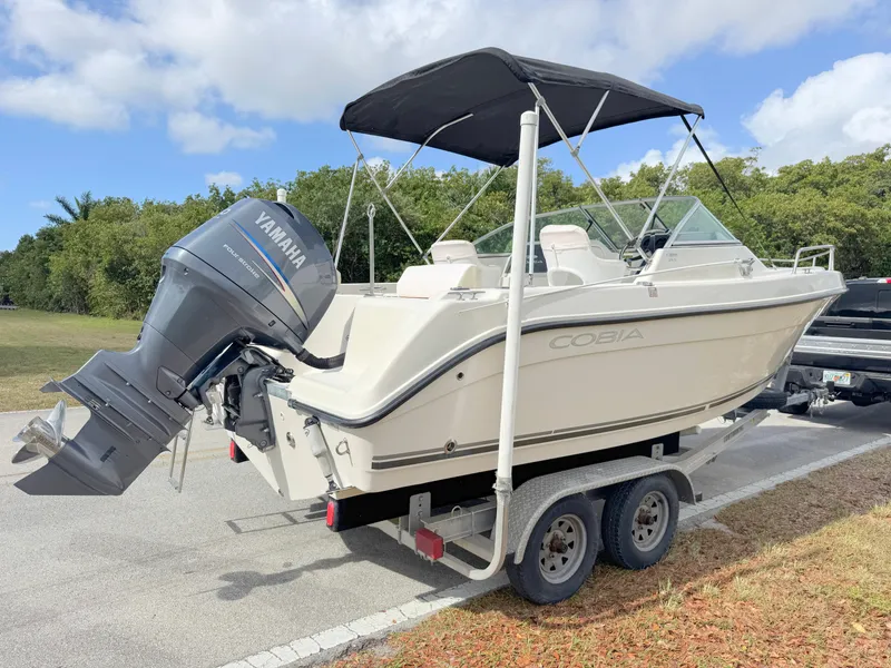 Slide: The Image of 2011 Cobia 215 Dual Console boat on trailer with Yamaha outboard motor, parked outdoors. - 5