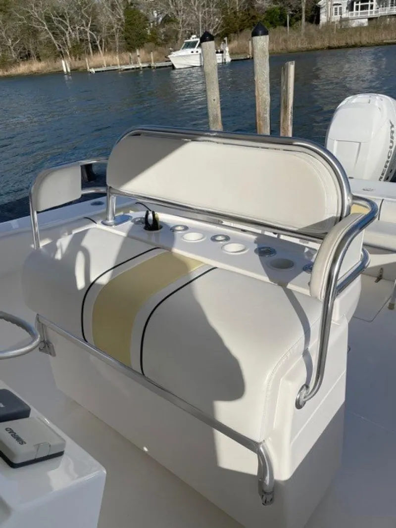 Slide: The Image of 2000 Venture 34 Center Console boat with cushioned seating and rod holders, docked by the water. - 6