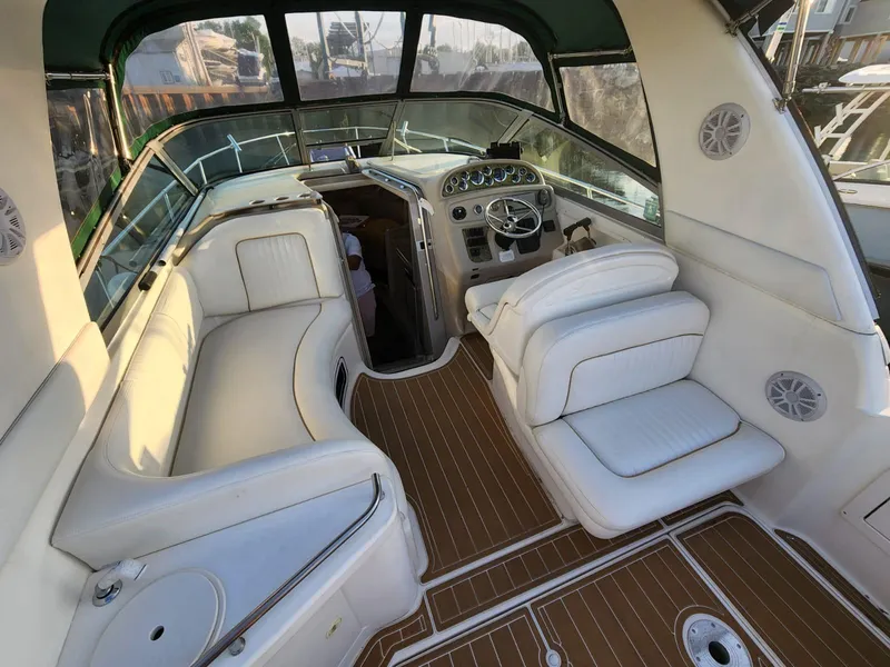 Slide: The Image of 1999 Sea Ray 290 Sundancer boat interior with white seating and wood flooring. - 2