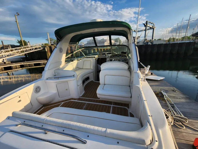 Slide: The Image of 1999 Sea Ray 290 Sundancer boat docked, featuring spacious seating and sleek design. - 3