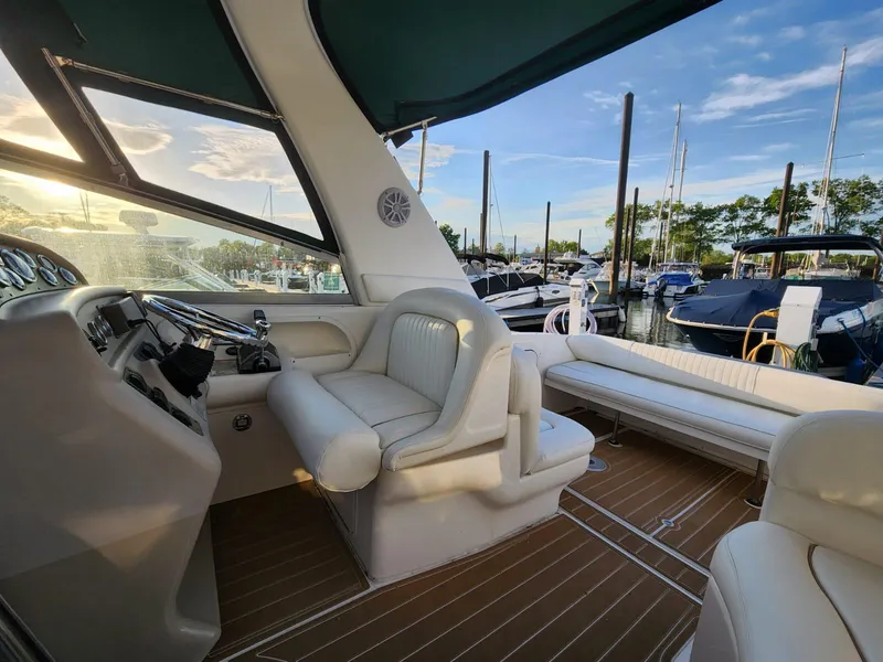 Slide: The Image of 1999 Sea Ray 290 Sundancer interior with white seating, docked at marina under blue sky. - 4