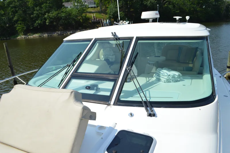 Slide: The Image of 2006 Tiara Yachts 4300 Sovran with sleek windshield design, docked by a serene river. - 11