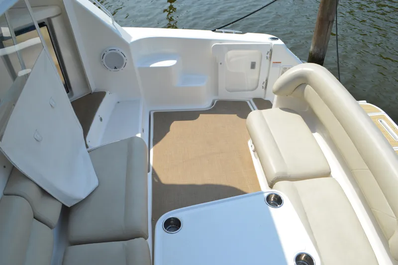 Slide: The Image of 2006 Tiara Yachts 4300 Sovran cockpit with beige seating and table, docked by water. - 17