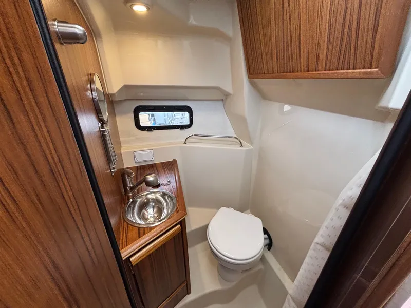 Slide: The Image of 2025 Ranger Tugs R-25 bathroom with wood accents, sink, and toilet. - 13