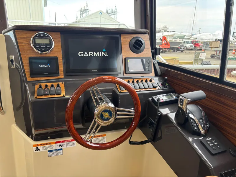 Slide: The Image of 2025 Ranger Tugs R-25 helm with Garmin navigation system and wooden steering wheel. - 7