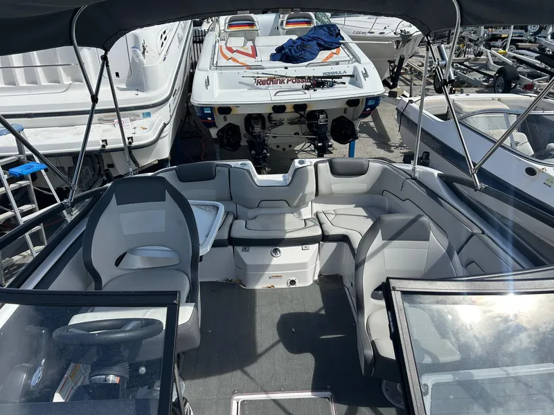 Slide: The Image of 2022 Yamaha Boats SX190 interior with seating and steering, docked among other boats. - 10