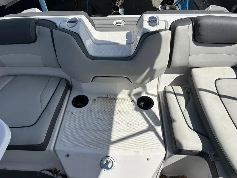 Slide: The Image of 2022 Yamaha Boats SX190 interior seating area with cup holders and gray upholstery. - 11