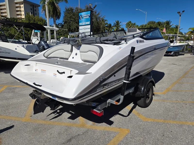 Slide: The Image of 2022 Yamaha Boats SX190 on trailer, parked outdoors under clear blue sky. - 2