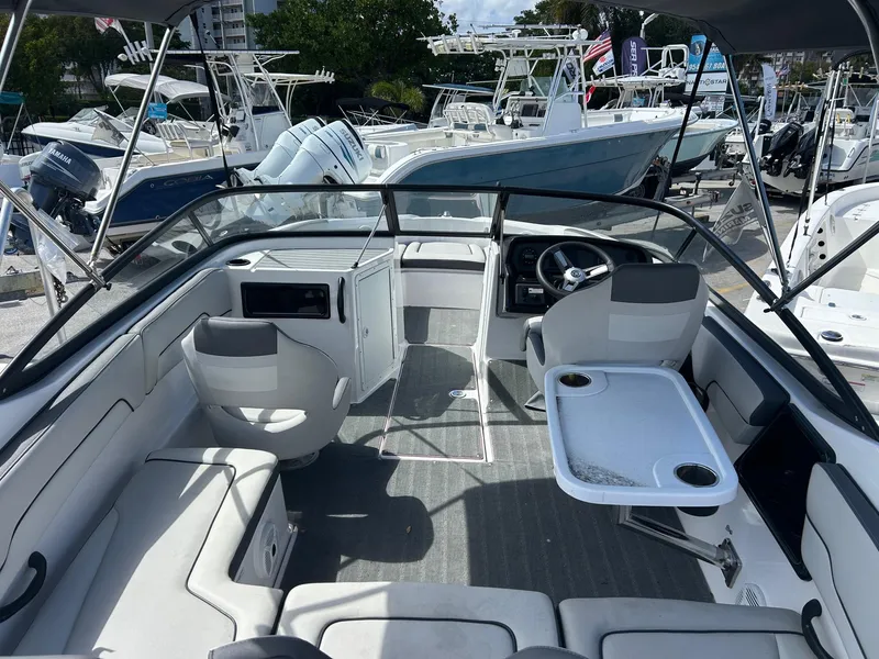 Slide: The Image of 2022 Yamaha Boats SX190 interior with seating, table, and steering wheel, docked among other boats. - 4