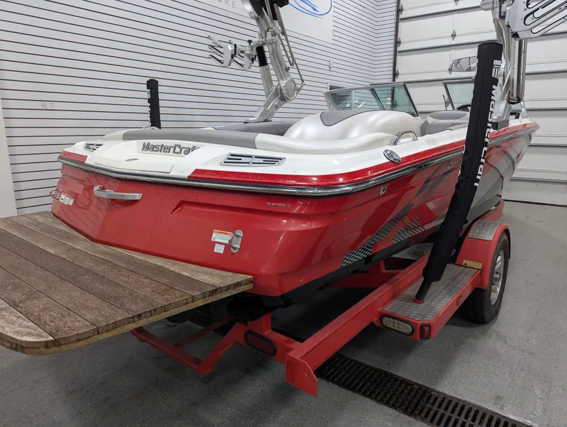 Slide: The Image of 2012 MasterCraft X-14 boat in a garage, red exterior, on a trailer. - 2