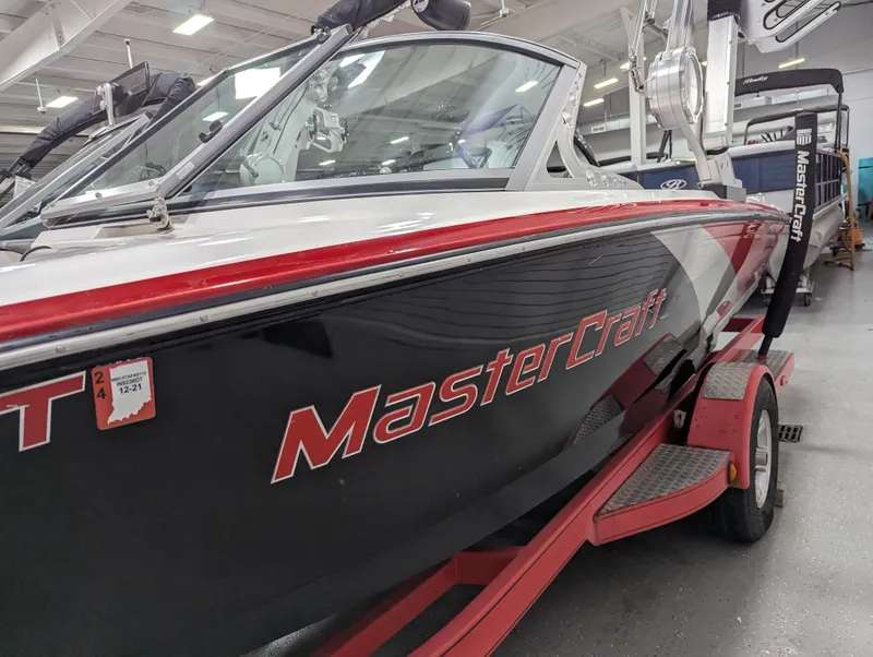 Slide: The Image of 2012 MasterCraft X-14 boat with red accents on a trailer in a showroom. - 6