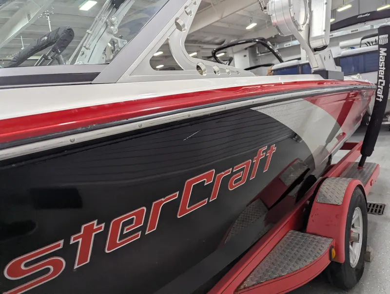 Slide: The Image of 2012 MasterCraft X-14 boat on trailer, red and black design, indoor showroom. - 7
