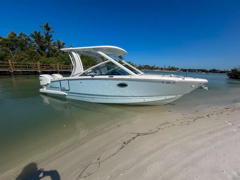 Slide: The Image of 2024 Chaparral 280 OSX boat docked on a sandy beach with clear blue skies. - 0