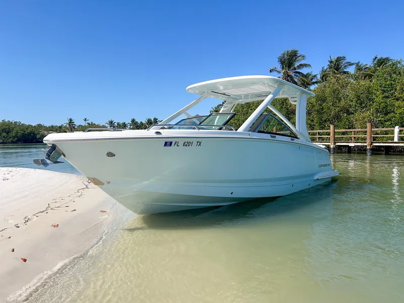 Slide: The Image of 2024 Chaparral 280 OSX boat docked on a sandy beach with clear blue skies. - 1