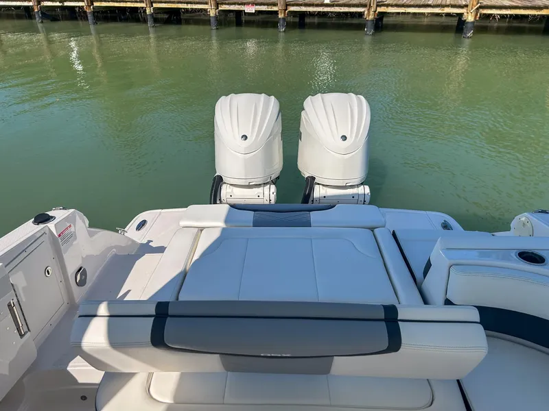 Slide: The Image of 2024 Chaparral 280 OSX boat with dual outboard engines docked on calm water. - 12