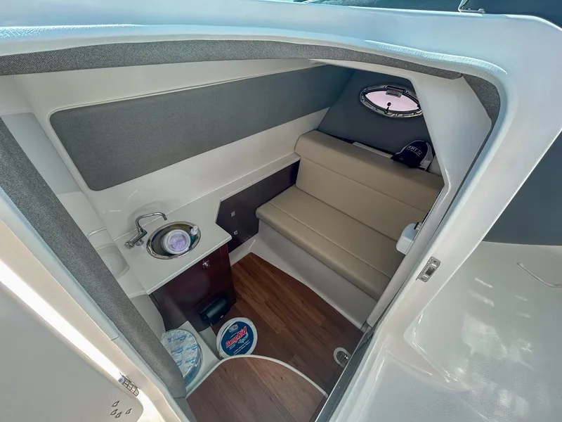 Slide: The Image of 2024 Chaparral 280 OSX cabin interior with seating, sink, and porthole window. - 16