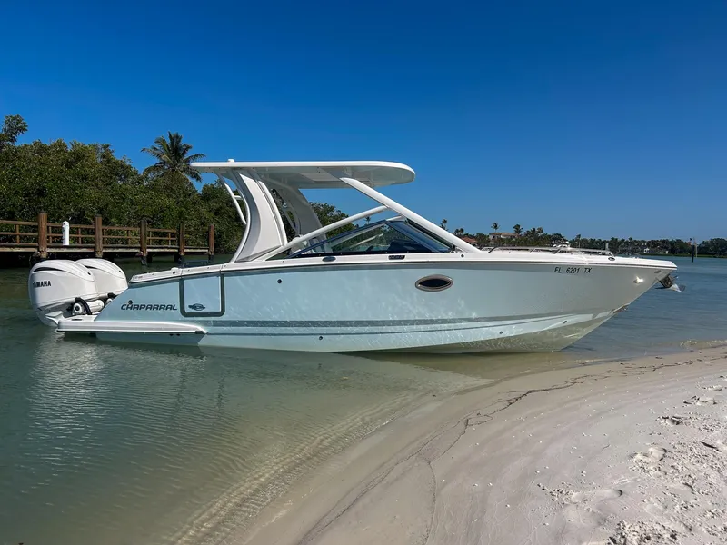 Slide: The Image of 2024 Chaparral 280 OSX boat beached on sandy shore under clear blue sky. - 2