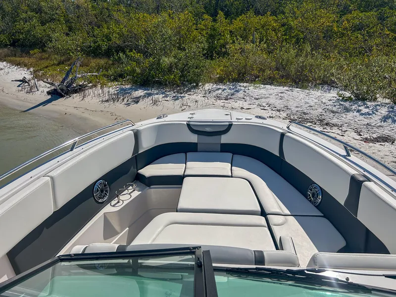 Slide: The Image of 2024 Chaparral 280 OSX boat with spacious seating, docked on a sandy beach. - 6