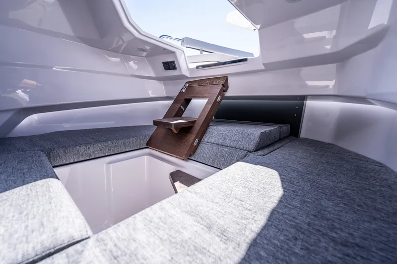 Slide: The Image of 2025 Axopar 29 Sun Top interior cabin with gray cushions and wooden accents. - 13