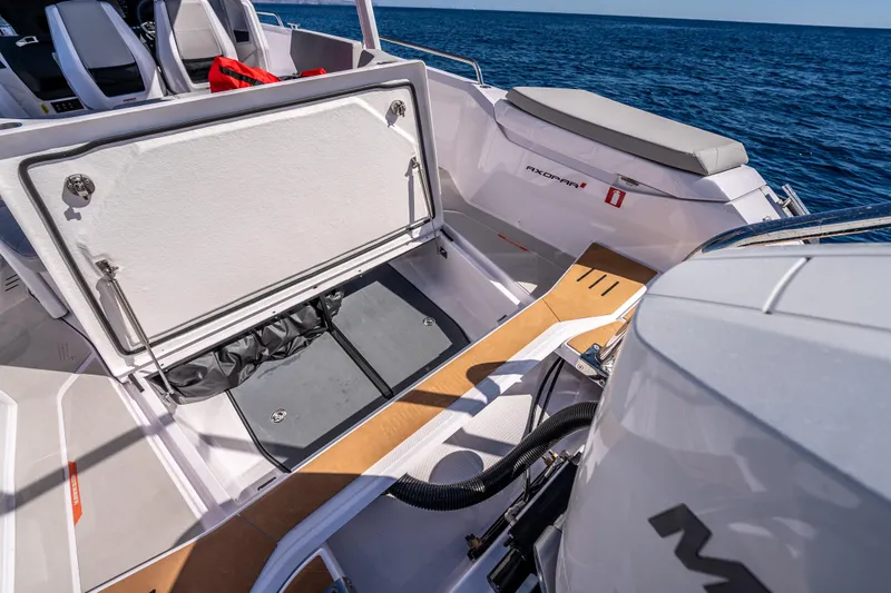 Slide: The Image of 2026 Axopar 29 Sun Top boat interior with open storage compartment, ocean backdrop. - 14