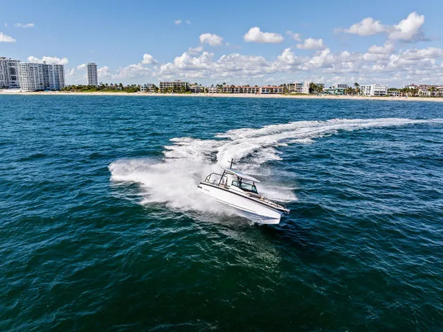 Slide: The Image of 2026 Axopar 29 Sun-Top boat cruising on open sea under clear blue sky. - 27