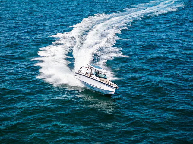 Slide: The Image of 2026 Axopar 29 Sun-Top boat on serene water with scenic shoreline view. - 31