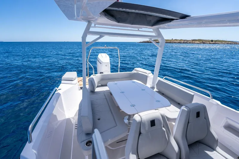 Slide: The Image of 2025 Axopar 29 Sun Top boat interior with modern dashboard and steering, overlooking the ocean. - 4