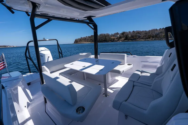 Slide: The Image of 2026 Axopar 29 Sun-Top boat interior with seating and table on calm water. - 51
