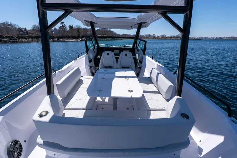 Slide: The Image of 2026 Axopar 29 Sun-Top boat with spacious seating and table on calm water. - 56