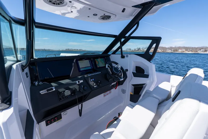Slide: The Image of 2026 Axopar 29 Sun-Top boat interior with modern dashboard and steering, overlooking serene waters. - 59