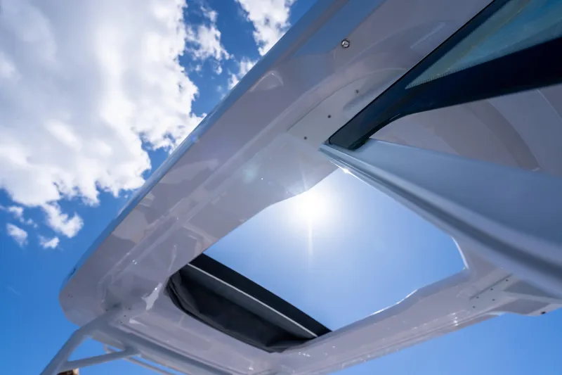 Slide: The Image of 2025 Axopar 29 Sun Top boat interior with modern dashboard, steering wheel, and ocean view. - 8