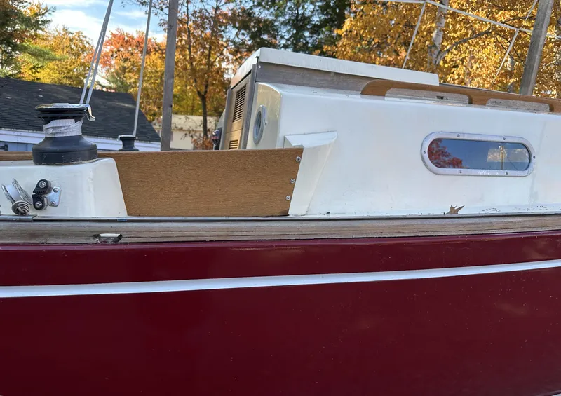 Slide: The Image of 1968 Allied Greenwich 24 sailboat with red hull and white cabin, docked in autumn setting. - 5