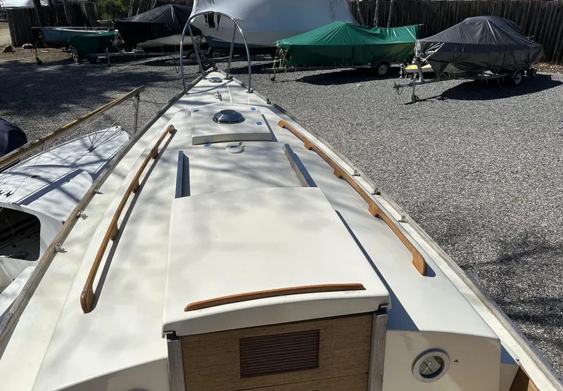 Slide: The Image of 1968 Allied Greenwich 24 sailboat deck with wooden handrails, parked on gravel. - 6