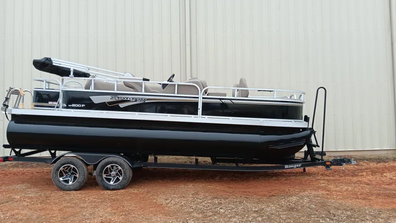 Slide: The Image of 2022 Ranger 200F pontoon boat on trailer, parked outdoors. - 11