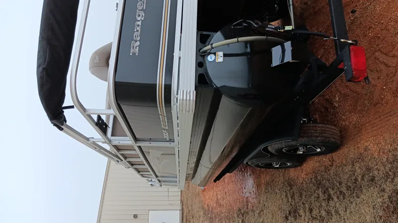 Slide: The Image of 2022 Ranger 200F boat on trailer, parked on gravel near a building. - 14