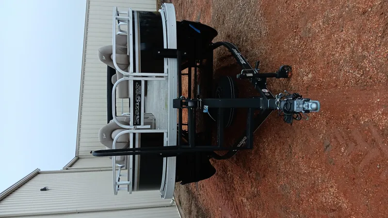 Slide: The Image of 2022 Ranger 200F boat on trailer, parked on red dirt near a building. - 24