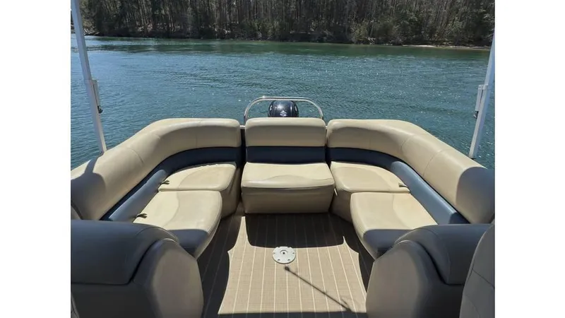 Slide: The Image of 2019 Manitou 23 Aurora LE Bar pontoon boat interior with beige seating on a lake. - 10