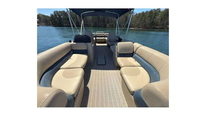 Slide: The Image of 2019 Manitou 23 Aurora LE Bar pontoon boat interior with beige seating on a lake. - 12