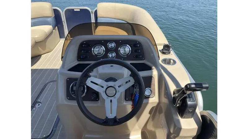 Slide: The Image of 2019 Manitou 23 Aurora LE Bar boat dashboard with steering wheel and controls on water. - 16